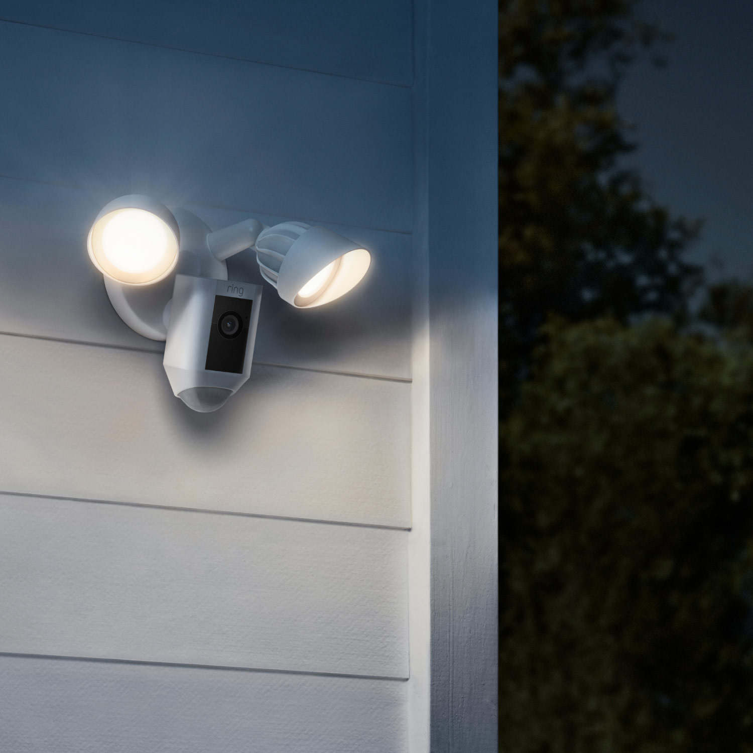 Front and Backyard Enhanced Kit (Spotlight Cam Plus Battery + Floodlight Cam Wired Plus) - White Ring Floodlight Cam Wired Plus mounted outdoors at night, with both LED floodlights turned on.