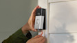 Hands installing a Ring Video Doorbell on a white wall