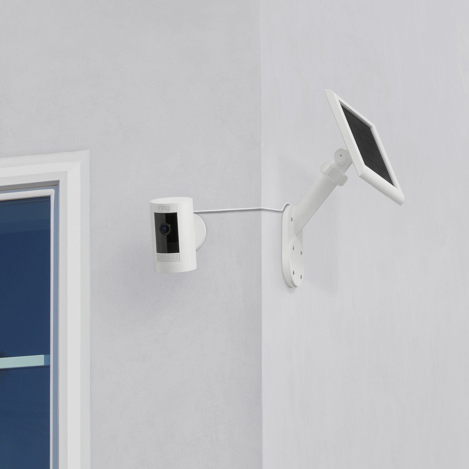 Wall Mount for Solar Panels and Cameras - Ring camera and solar panel mounted on white wall, connected by cable for continuous solar power.