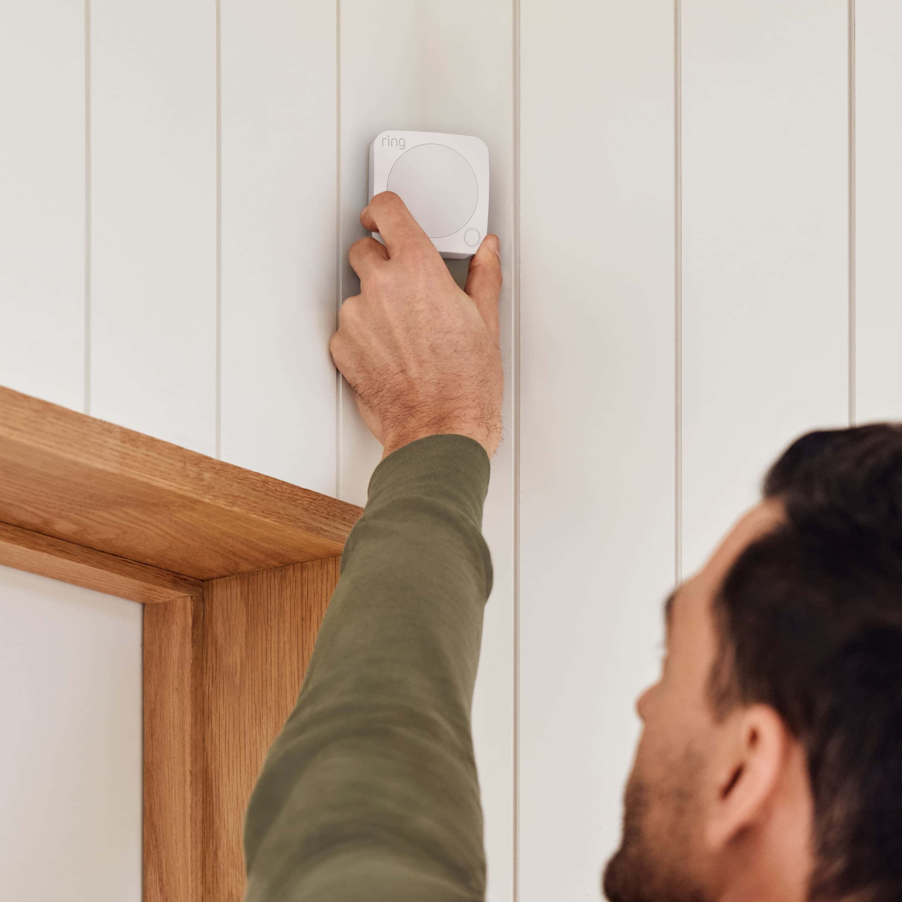 Alarm Security Kit, 8-Piece (2nd Generation) - Man installing a Ring Alarm Motion Detector on a wall above a doorway, showing easy setup of Ring Alarm Security Kit.