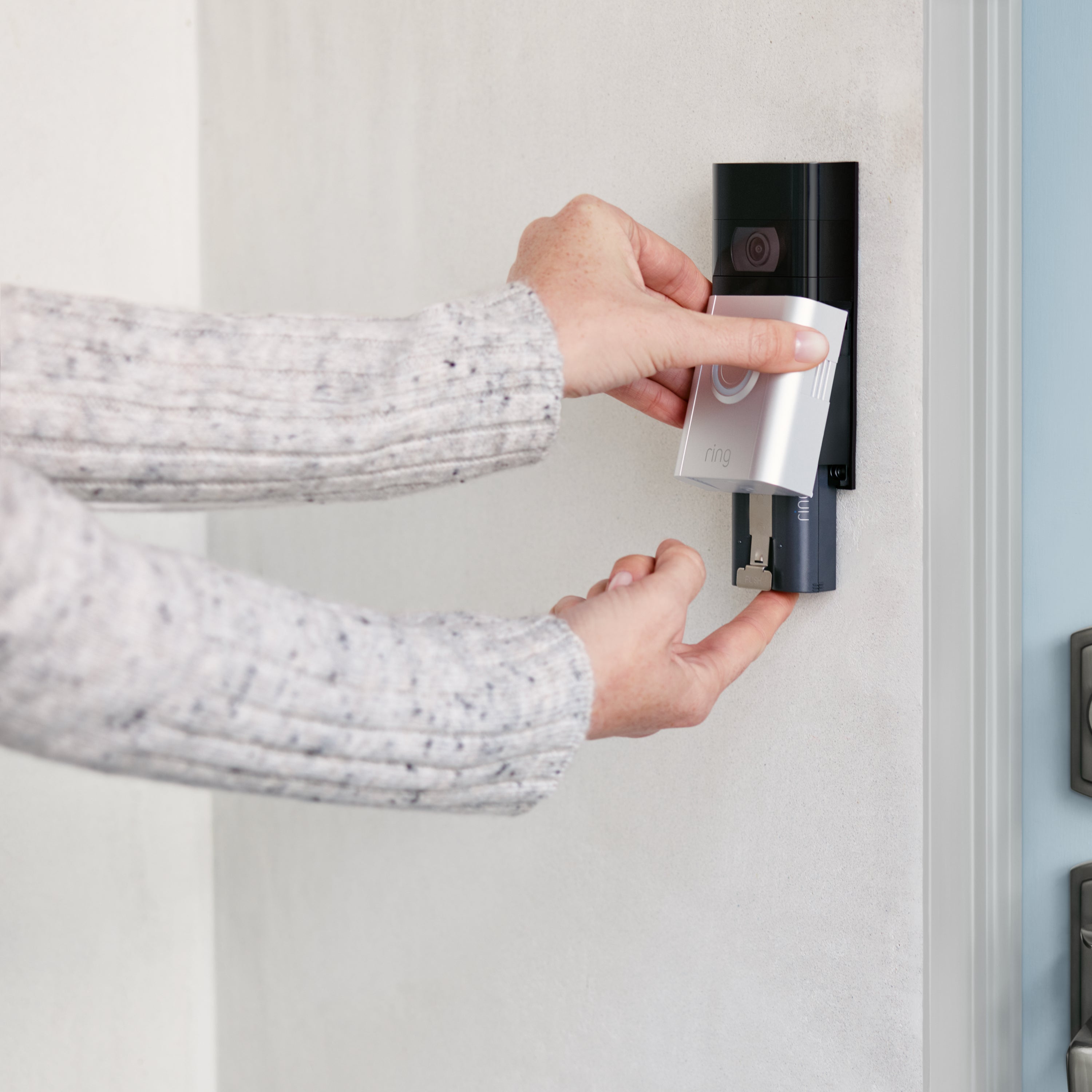 Charging Station + 2 Quick Release Battery Packs - Person removing a Ring Quick Release Battery Pack from a mounted Ring Video Doorbell, showing easy battery replacement.