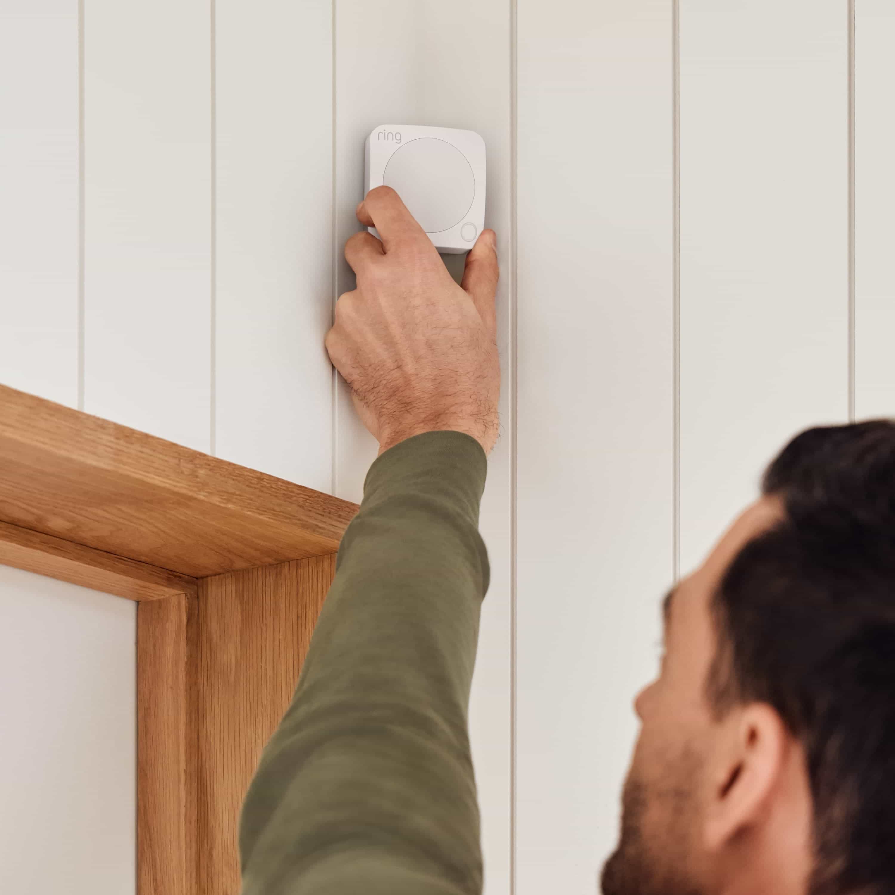 Alarm Security Kit, 14-Piece (2nd Generation) - Man installing a Ring Alarm Motion Detector on a wall above a doorway, showing easy setup.