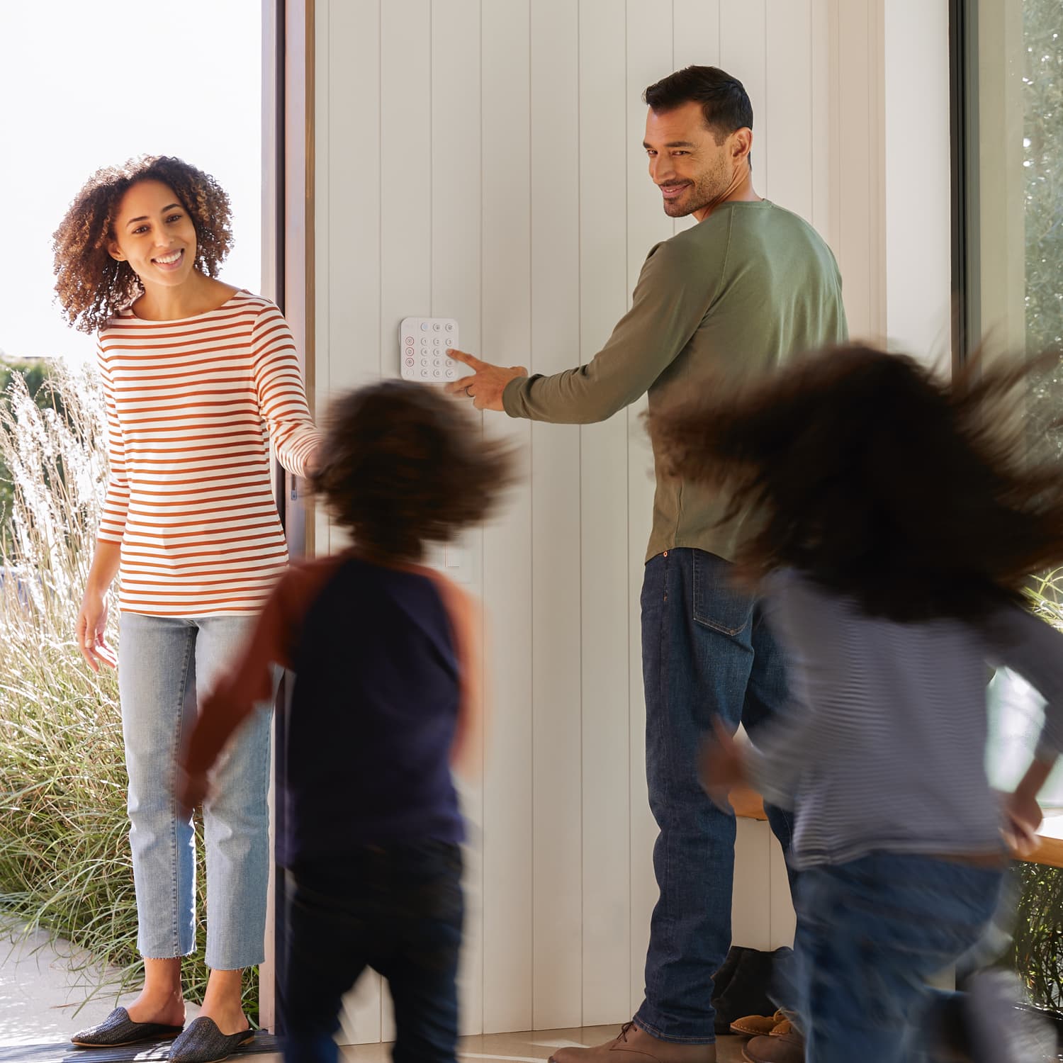 Alarm Security Kit, 8-Piece (2nd Generation) - Family exiting home as man uses a Ring Alarm Keypad on the wall, with two kids running toward a woman in doorway.