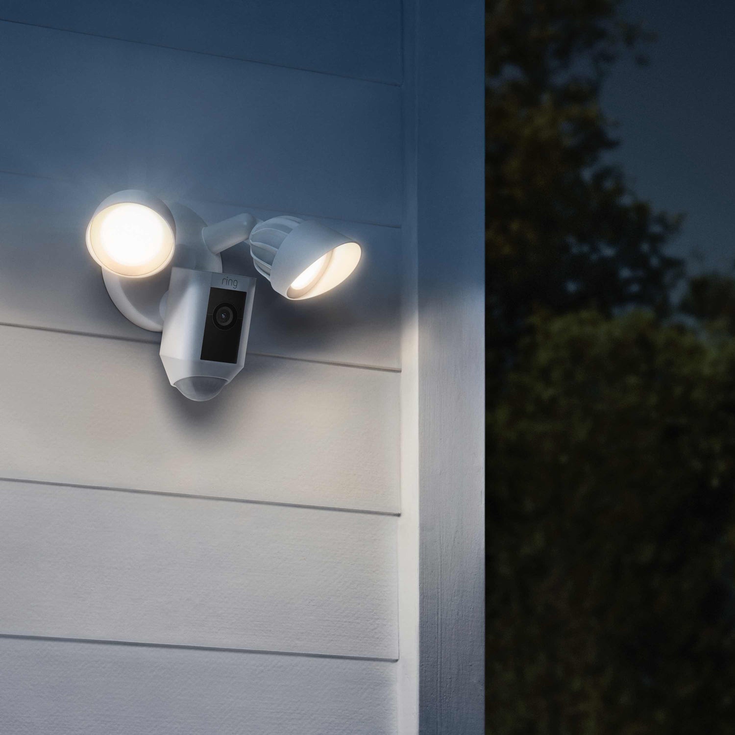 Floodlight Cam Wired Plus (Certified Refurbished) - Ring Floodlight Cam Wire Plus on wall at night, with motion-activated LED lights on.