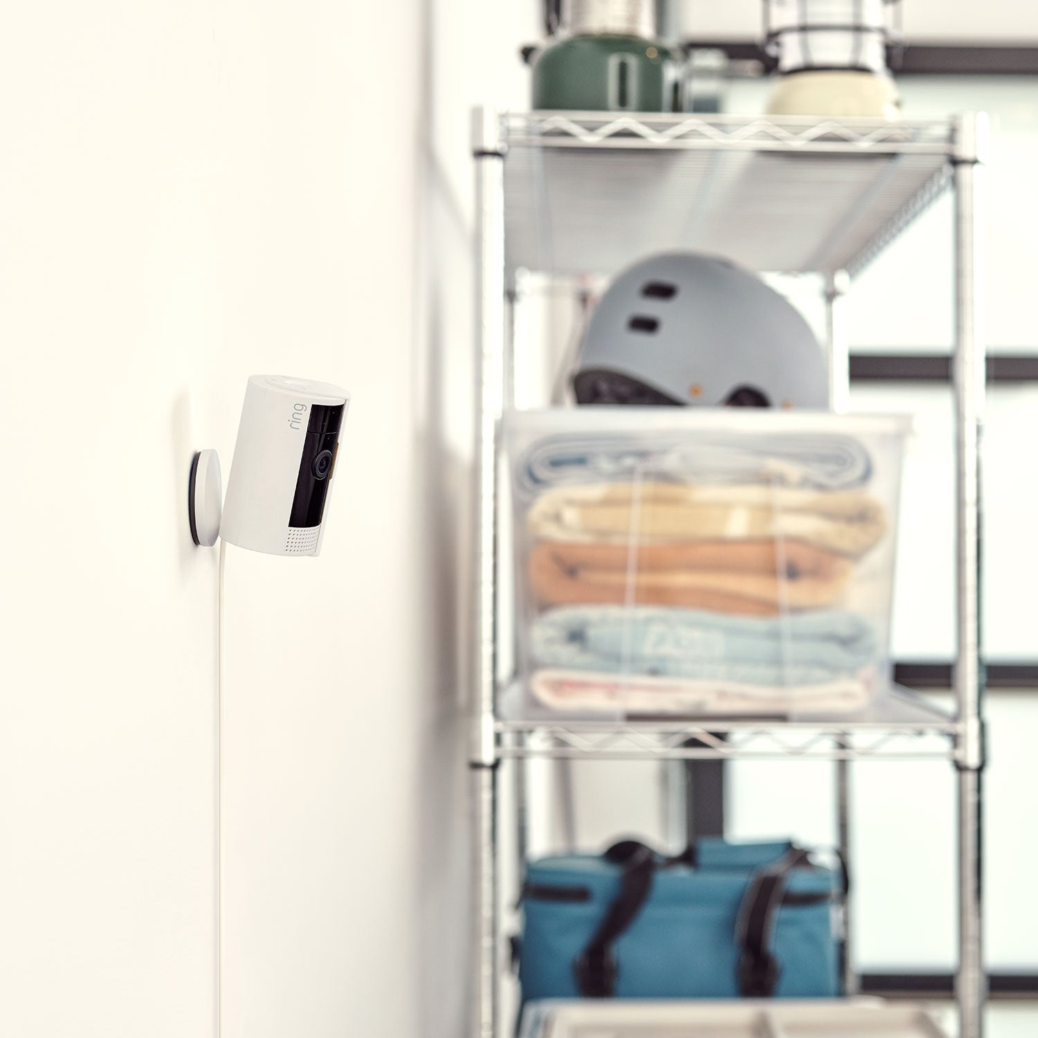 10 ft USB-A to Micro USB Power Cable (Indoor Cam (2nd Gen)) - Ring Indoor Cam 2nd Gen mounted on a wall with a  10-foot USB-A to Micro USB Power Cable, near shelves.