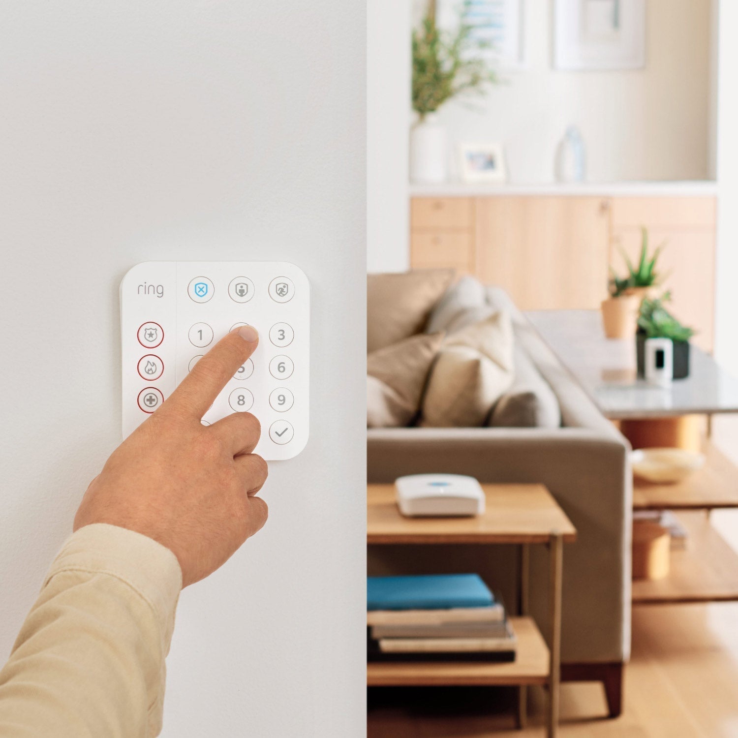 Whole Home Enhanced Kit (Battery Doorbell Plus + Spotlight Cam Plus Battery + Alarm Security Kit, 8-Piece) - Person using wall-mounted Ring Alarm Keypad, with living room in background.