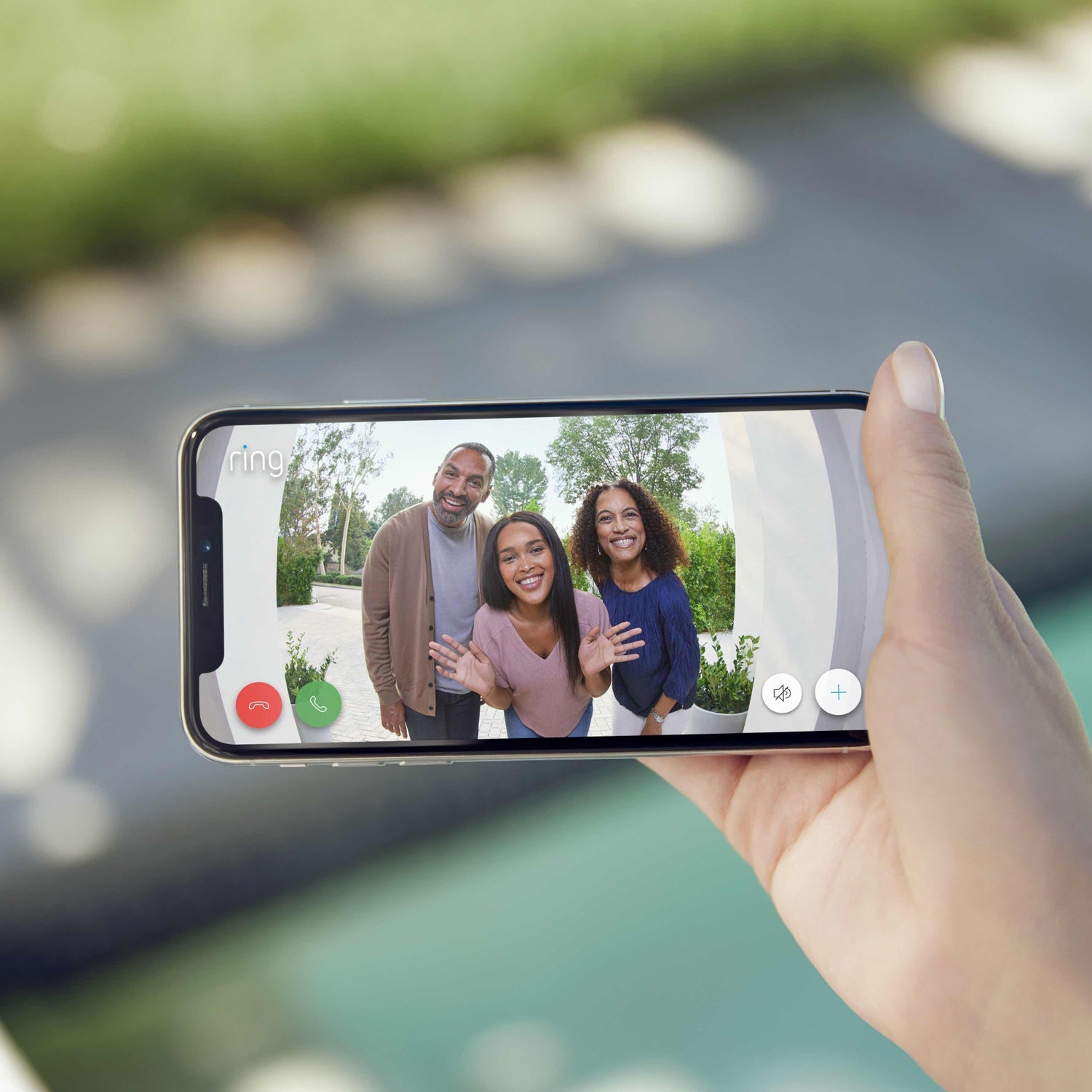 Wired Doorbell Plus (Video Doorbell Pro) (Certified Refurbished) - Hand holding phone showing live Ring video of three smiling visitors waving at the door.