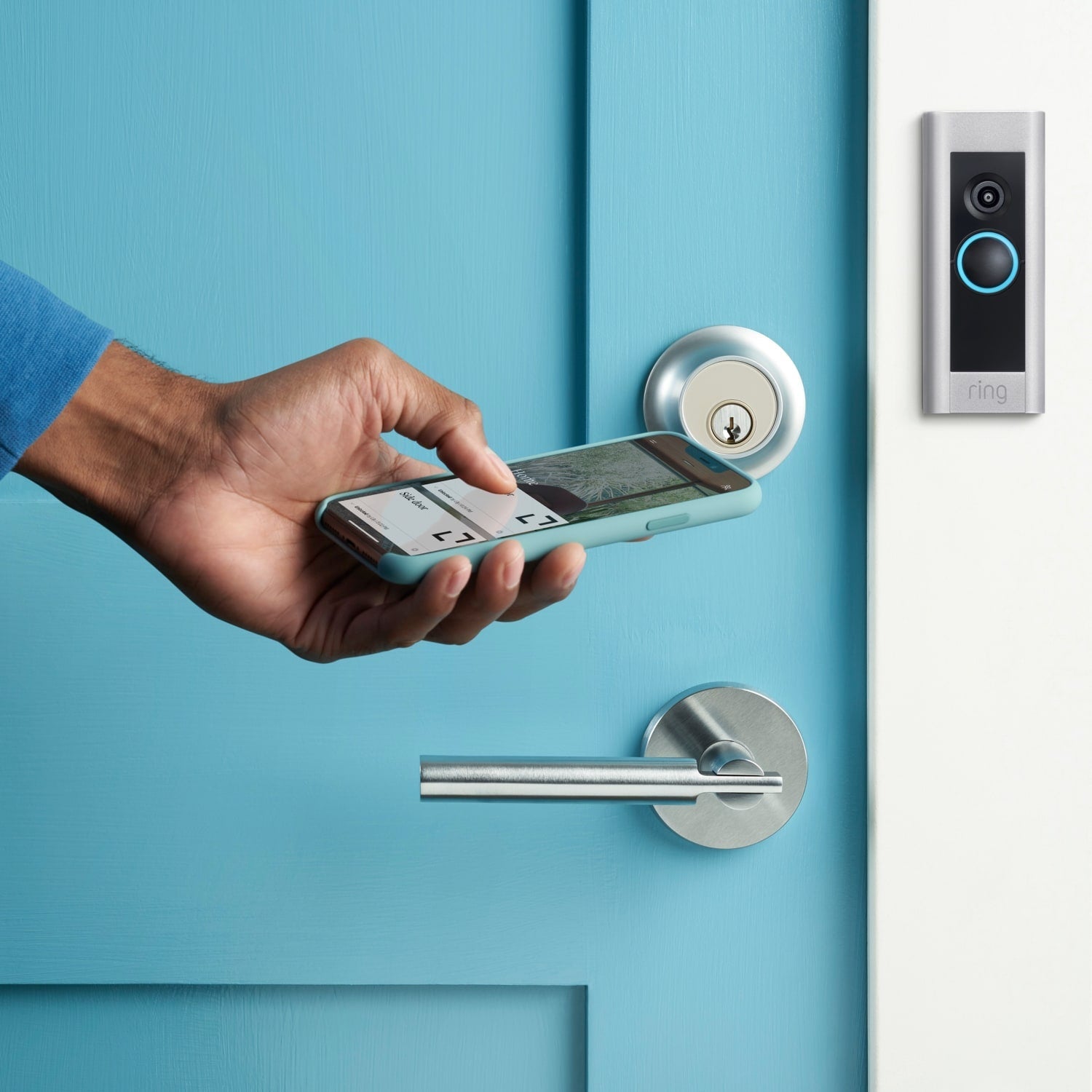 Wired Doorbell Plus (Video Doorbell Pro) (Certified Refurbished) - Hand holding a smartphone near a blue door with a smart lock and Ring Wired Doorbell Plus mounted beside it.