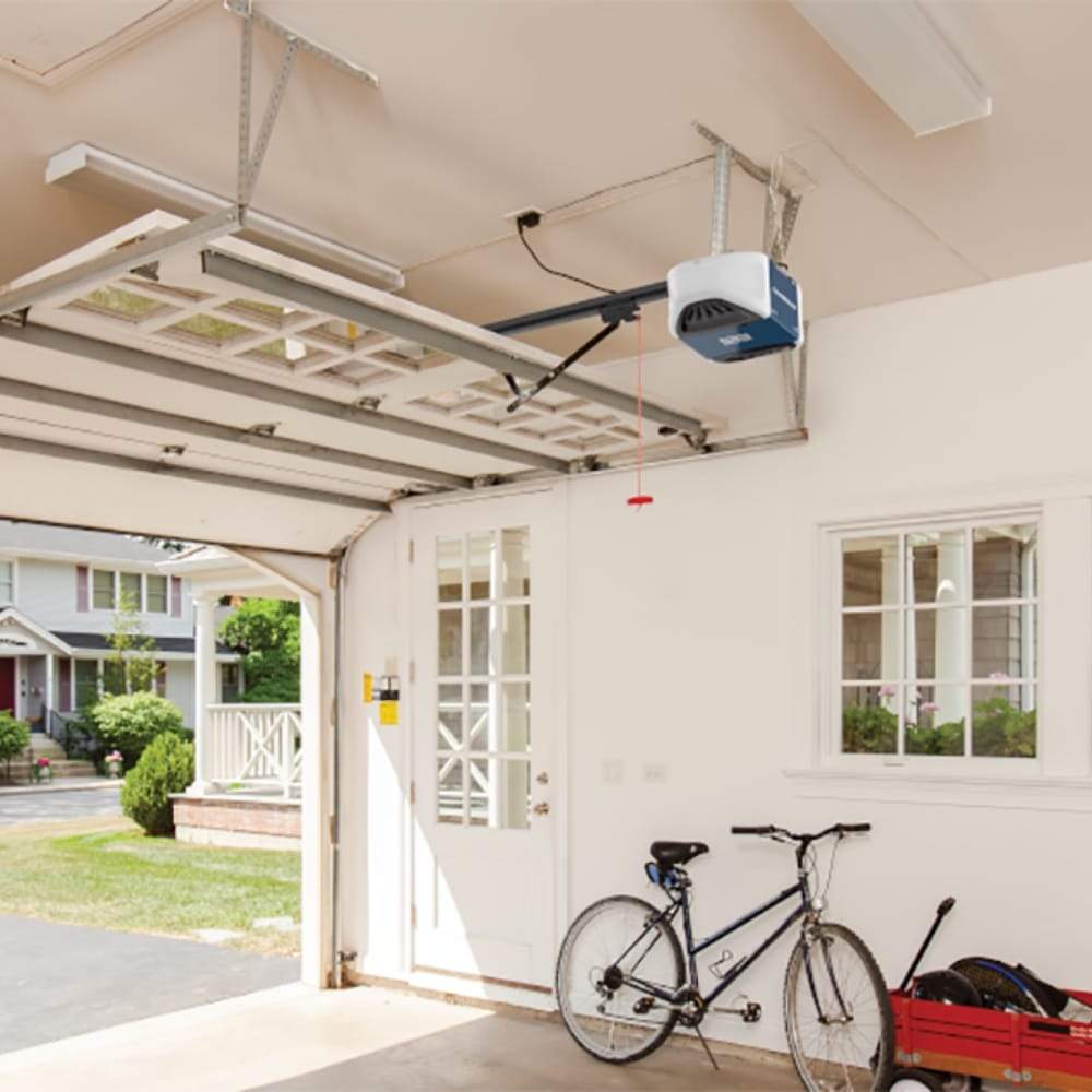 Chamberlain® Ultra-quiet belt drive Wi-Fi® Garage Door Opener (for Works with Ring) - Open garage showing ceiling-mounted Chamberlain Wi-Fi garage door opener, with a bicycle and red wagon against a wall.