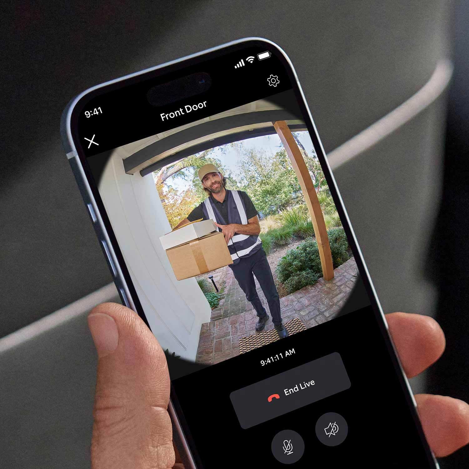 Protected Basic Kit (Battery Doorbell + Alarm 5-Piece Security Kit) - Hand holding a smartphone showing live Ring Battery Doorbell video of delivery person with packages at front door.