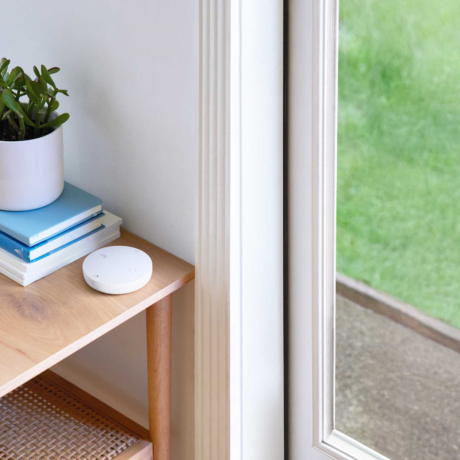 Glass Break Sensor (Newest Model) - White round Glass Break Sensor mounted on a side table near a window.