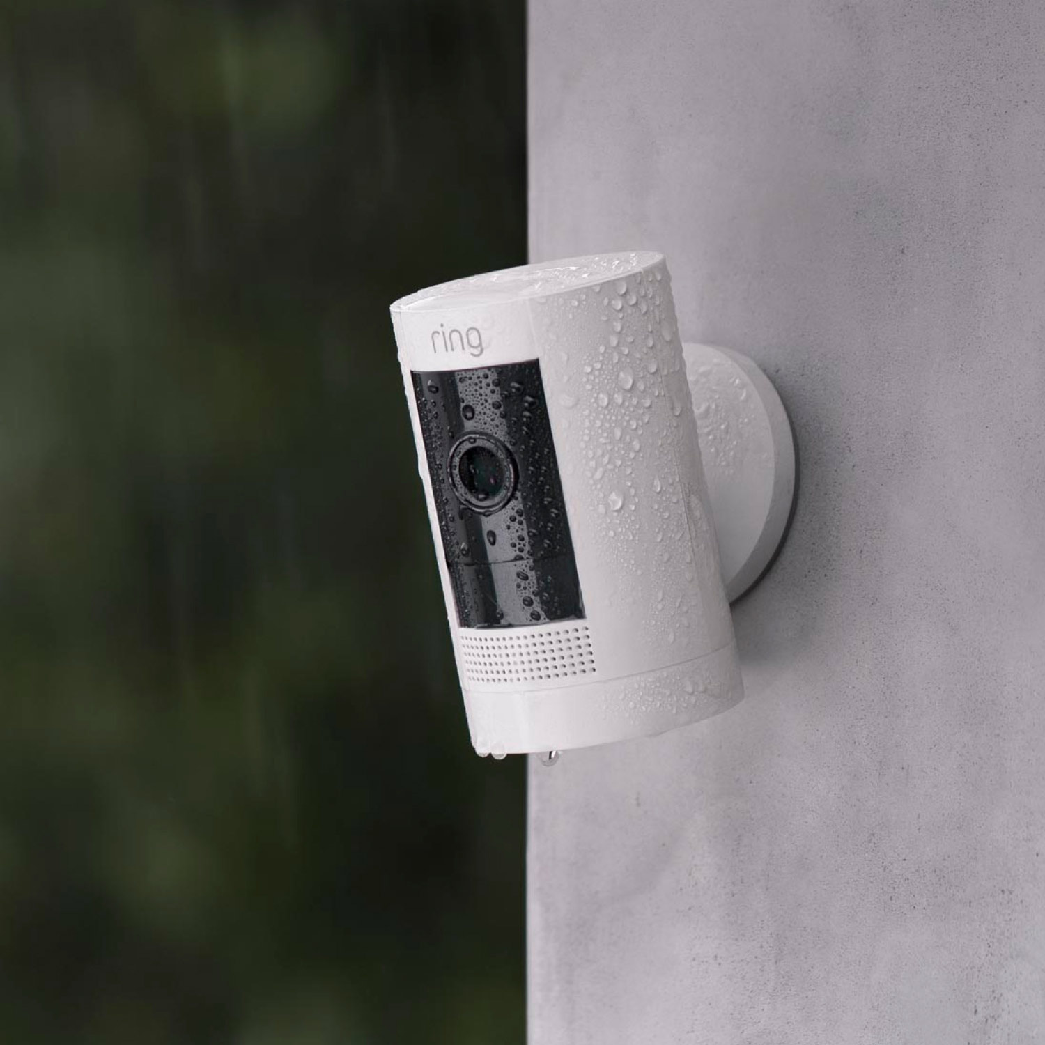 Outdoor Cam (Formerly: Stick Up Cam) - Battery:White Ring Outdoor Cam Stick Up on wall, covered in rain droplets, showing weather-resistant design.