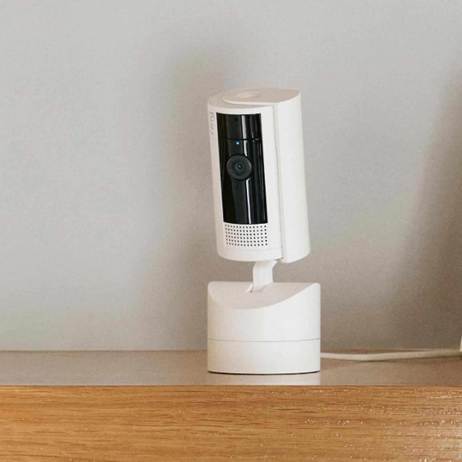 Retail Starter Kit (Plug-In) (Outdoor Cam Plus Plug-In + Pan-Tilt Indoor Cam) - White Pan-Tilt Indoor Cam inside on a wooden surface, slightly tilted to the left side.