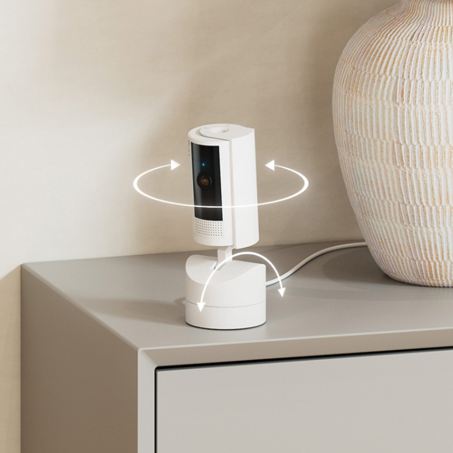 Pan-Tilt Indoor Cam + Spotlight Cam Plus Plug-In - White Ring Pan-Tilt Indoor Camera on a console table next to a lamp, shown with arrows indicating 360-degree rotation.