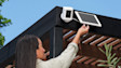 A person installing an outdoor Ring security camera and solar panel on a patio pergola