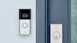 Ring Video Doorbell mounted on white door frame with blue illuminated button